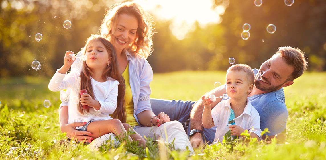 Emsan® Allergieprodukte Eine Familie mit zwei Kindern liegt auf einer Wiese.
