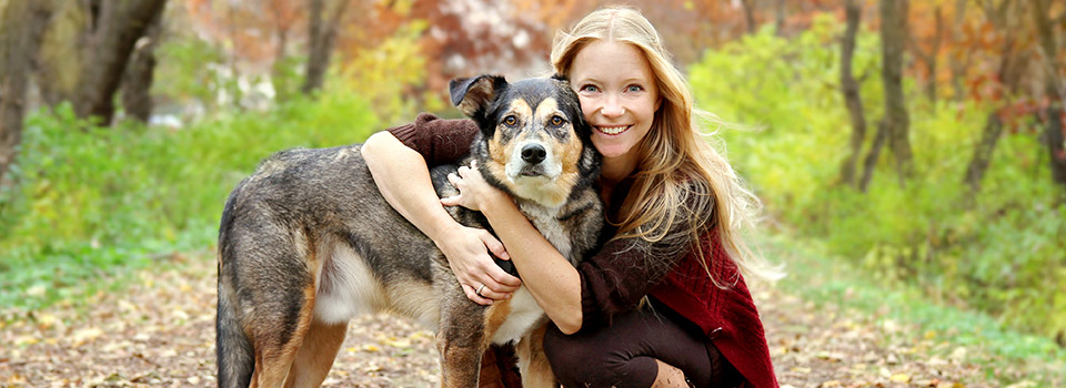 Eine junge Frau umarmt einen Hund.