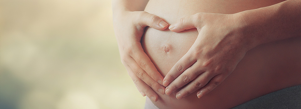 In der Schwangerschaft muss bei der Sinusitis-Behandlung sowohl an das Wohlergehen der Mutter als auch des Kindes gedacht werden. Eine Schwangere formt mit den Händen ein Herz auf ihrem Bauch.