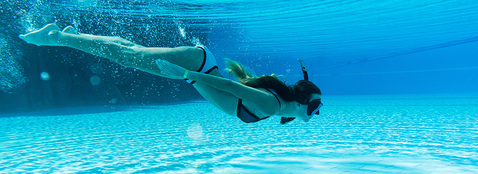 Ist die Nasenschleimhaut trocken, kann die Nase jucken und sich verstopft anfühlen. Unterwasseraufnahme von einer Frau, die in einem Pool taucht.